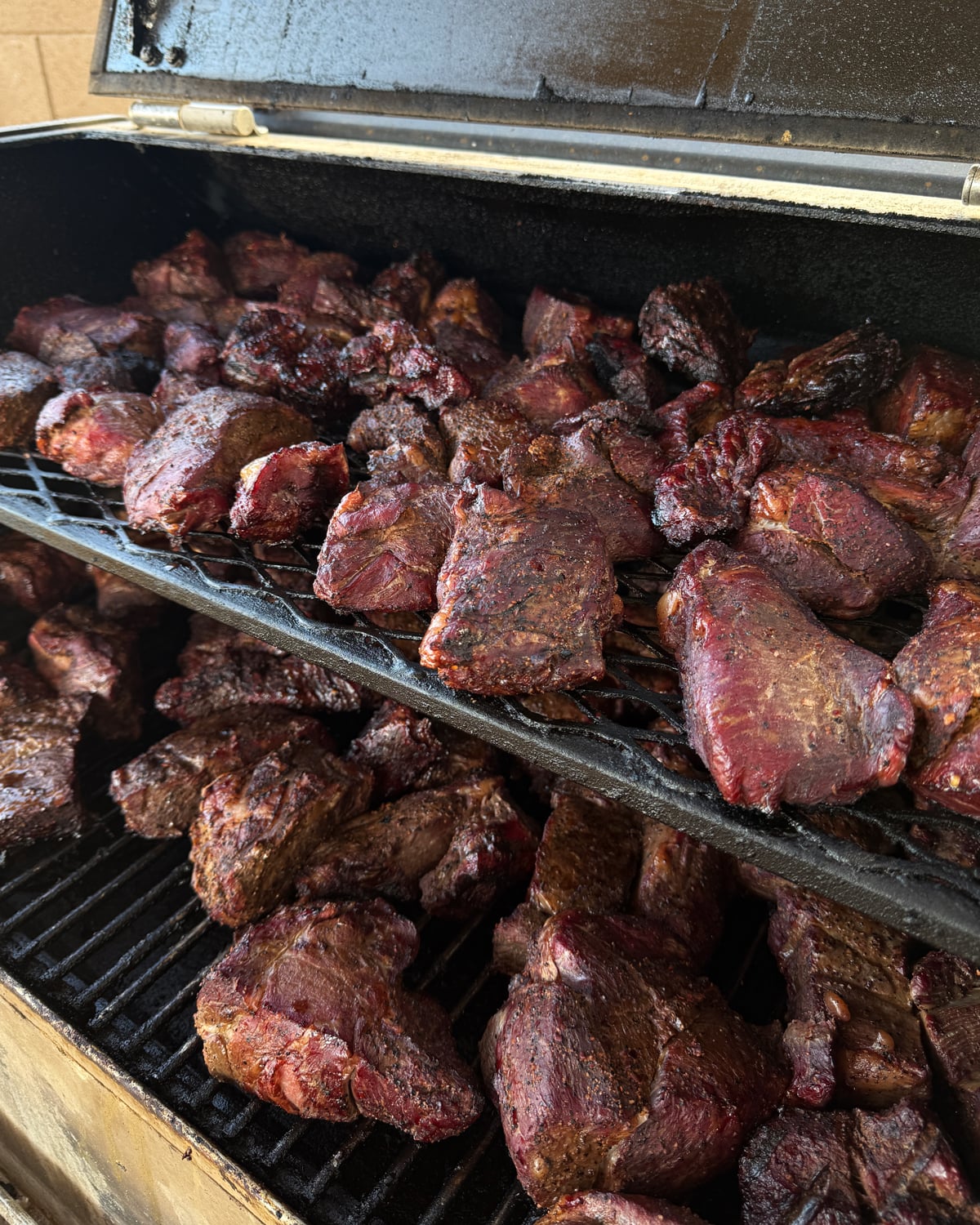 Chuck roast pieces smoking on a full offset smoker in bulk