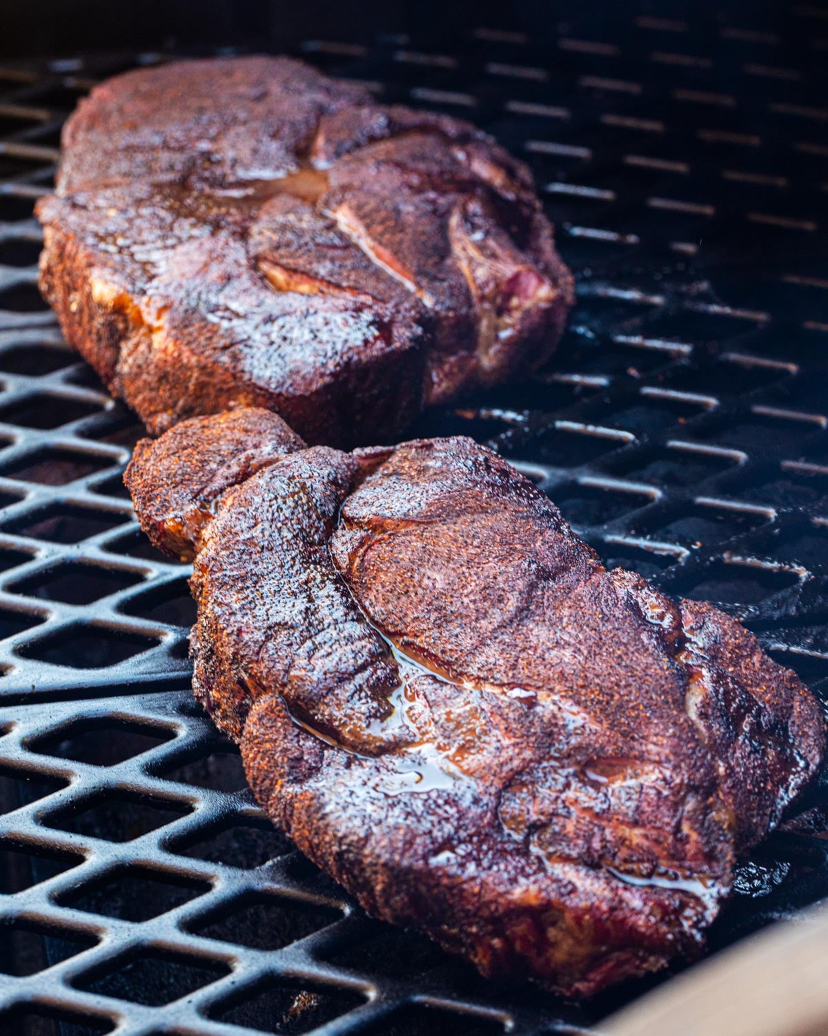 Two chuck roasts on smoker grates early in the smoke phase
