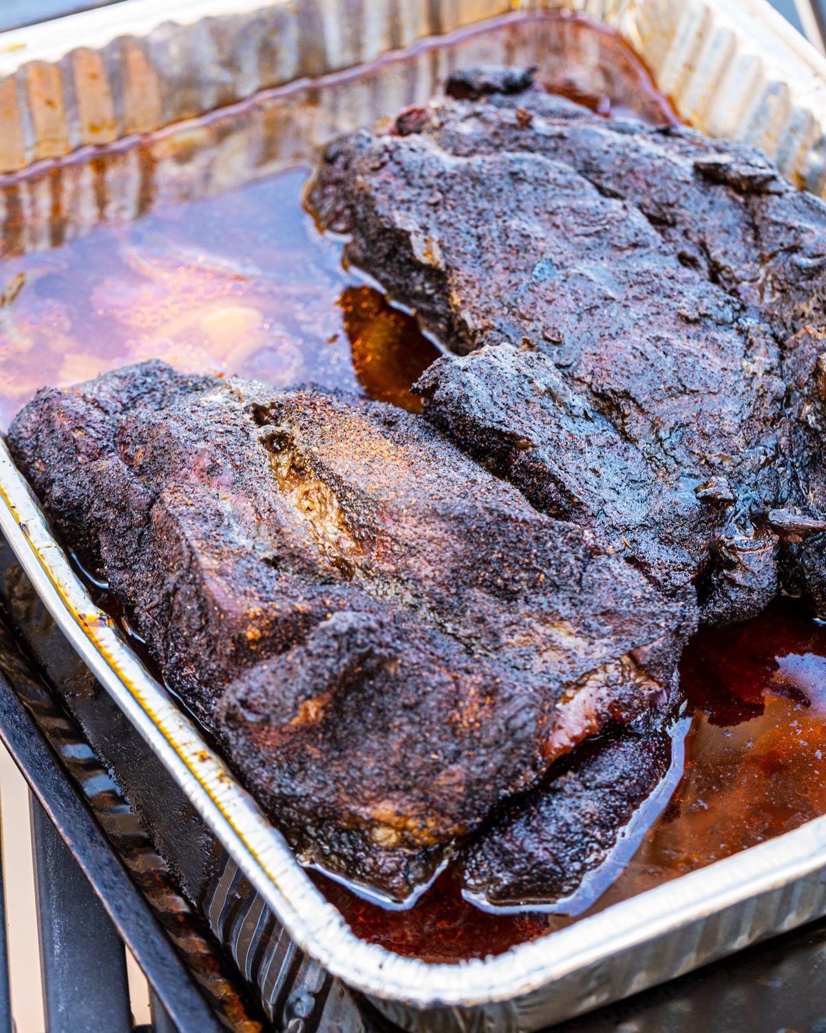 Chuck roasts in a foil pan with braising liquid before shredding