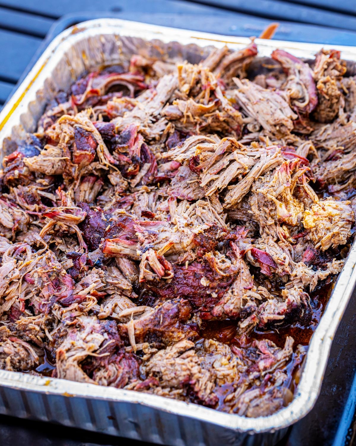 Smoked pulled beef shredded in a foil pan on the smoker
