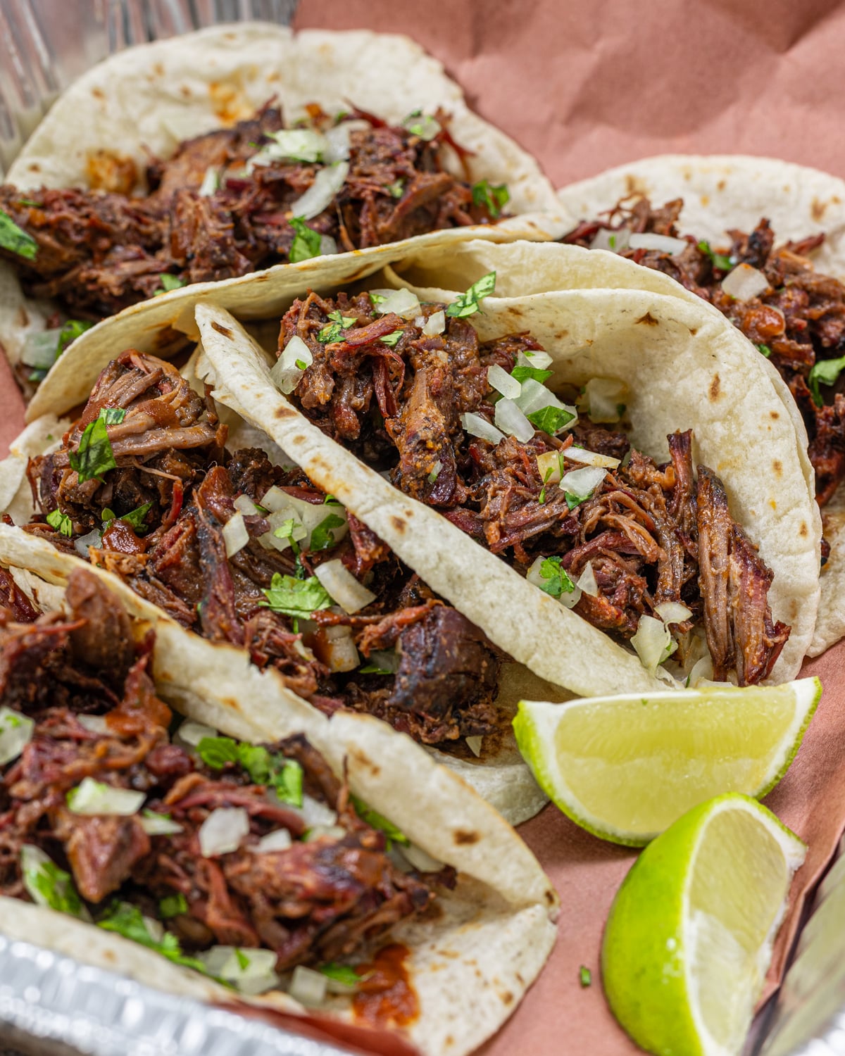 Smoked pulled beef tacos on flour tortillas with diced onion and cilantro
