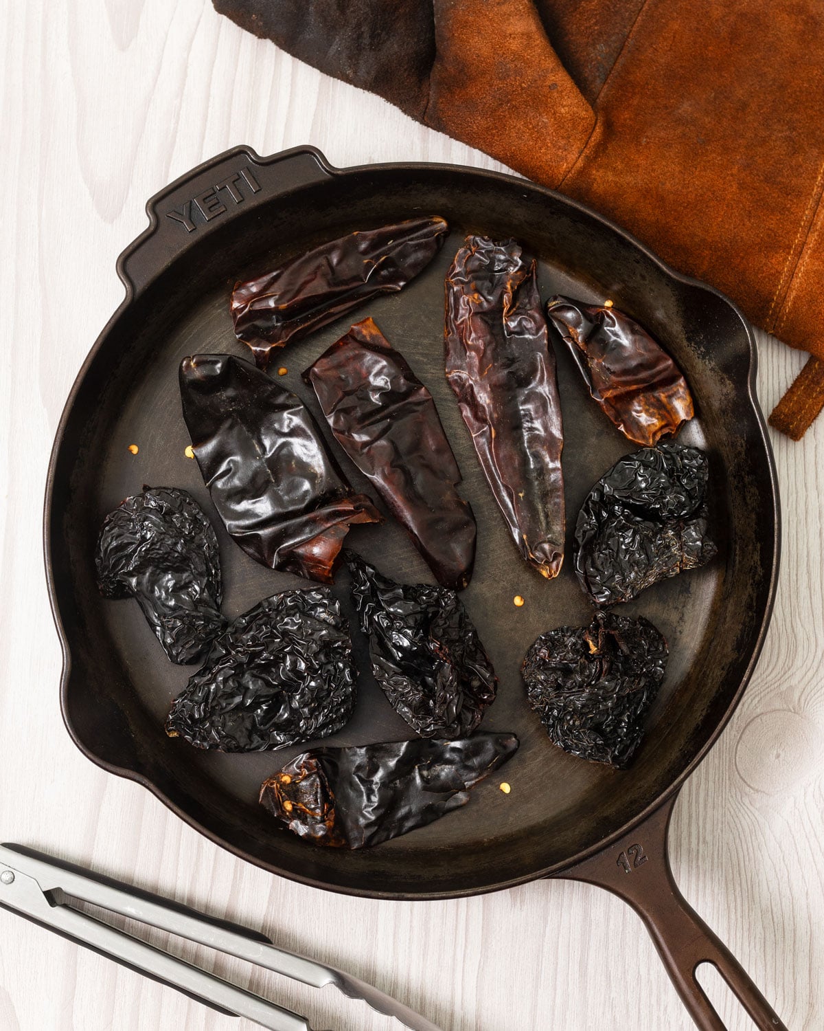 Dried ancho and guajillo chiles toasting in a cast iron skillet before making adobo sauce.