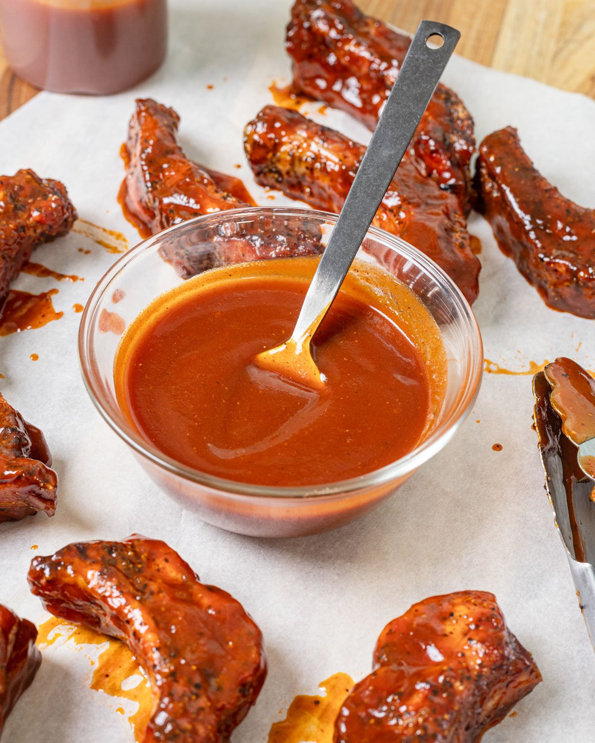 Spicy buffalo barbecue sauce in a bowl with sauced party ribs