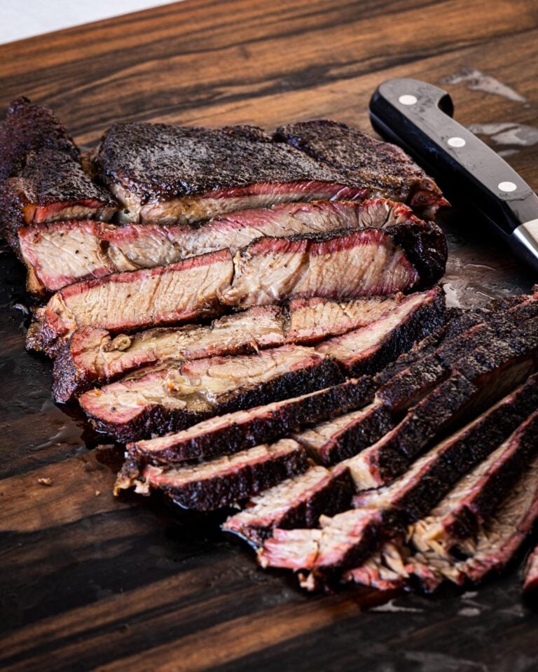 Smoked chuck roast sliced against the grain on a wood cutting board
