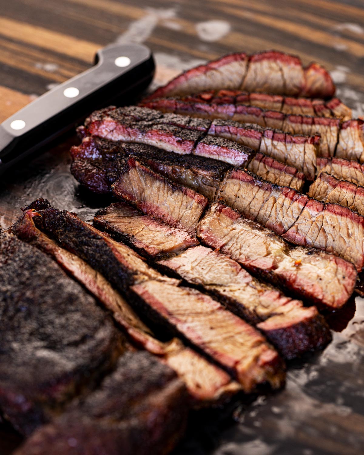 Smoked chuck roast sliced and spread on butcher paper with smoke ring visible