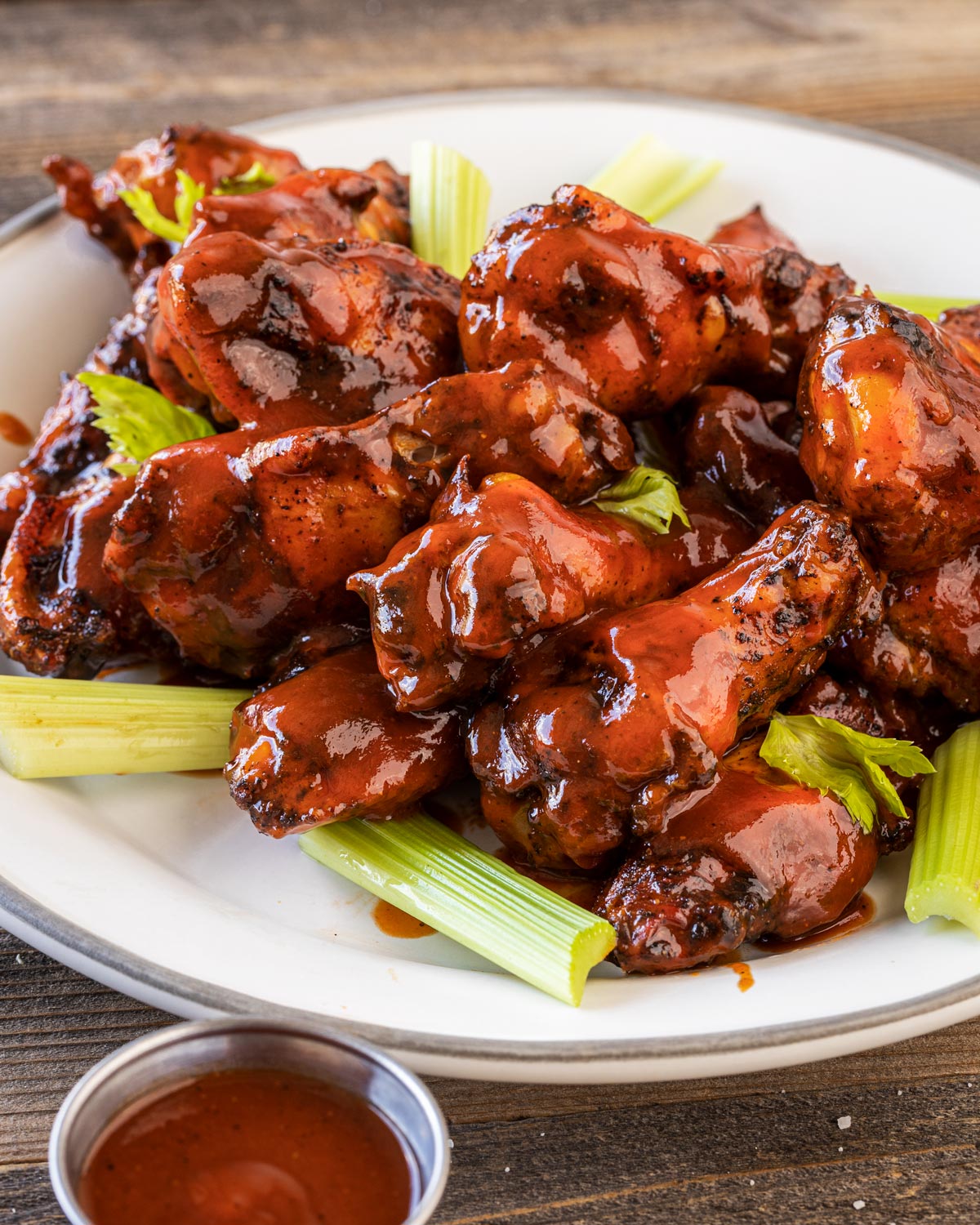 Close up shot of buffalo bbq wings on a plate with celery sticks