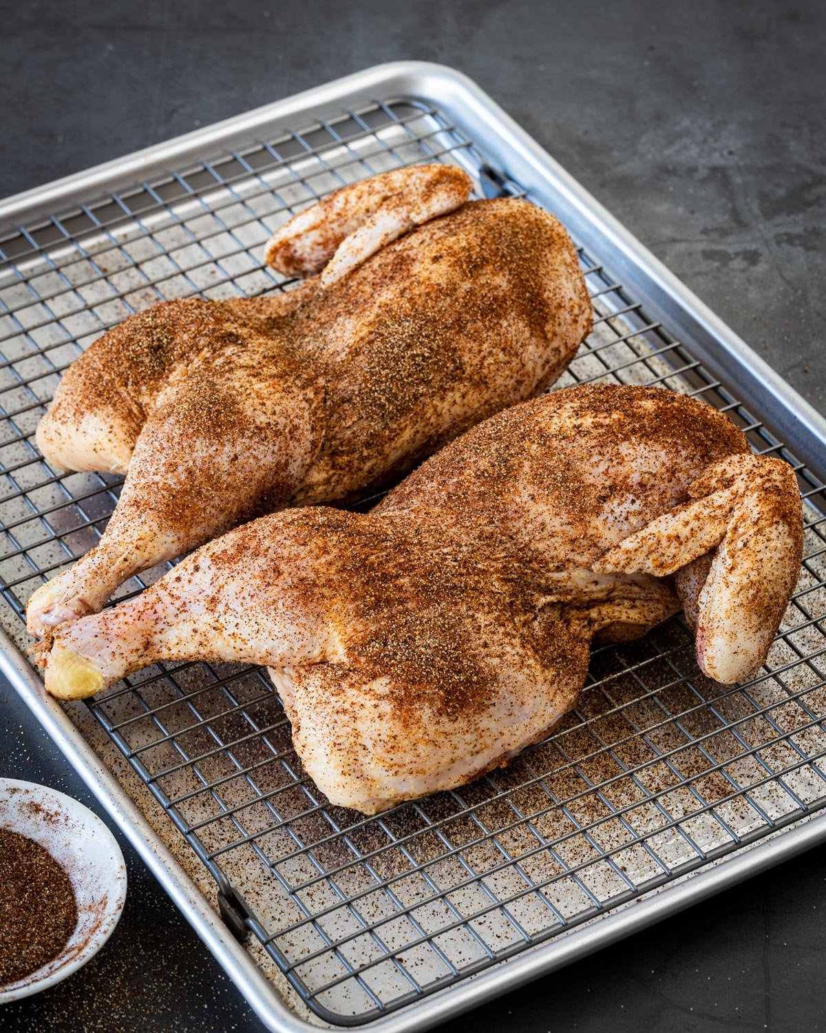 Seasoning the chicken halves on a wire rack. They will be dry-brined overnight.