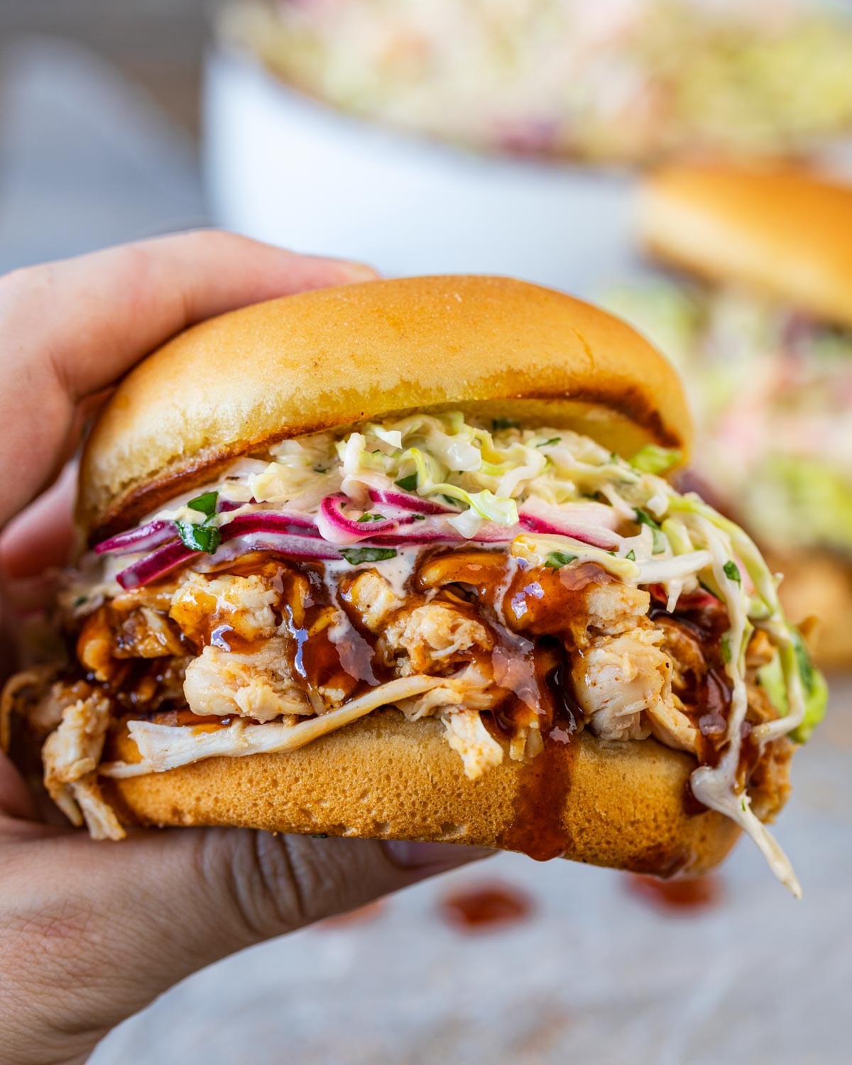 Holding an assembled bbq shredded chicken sandwich.