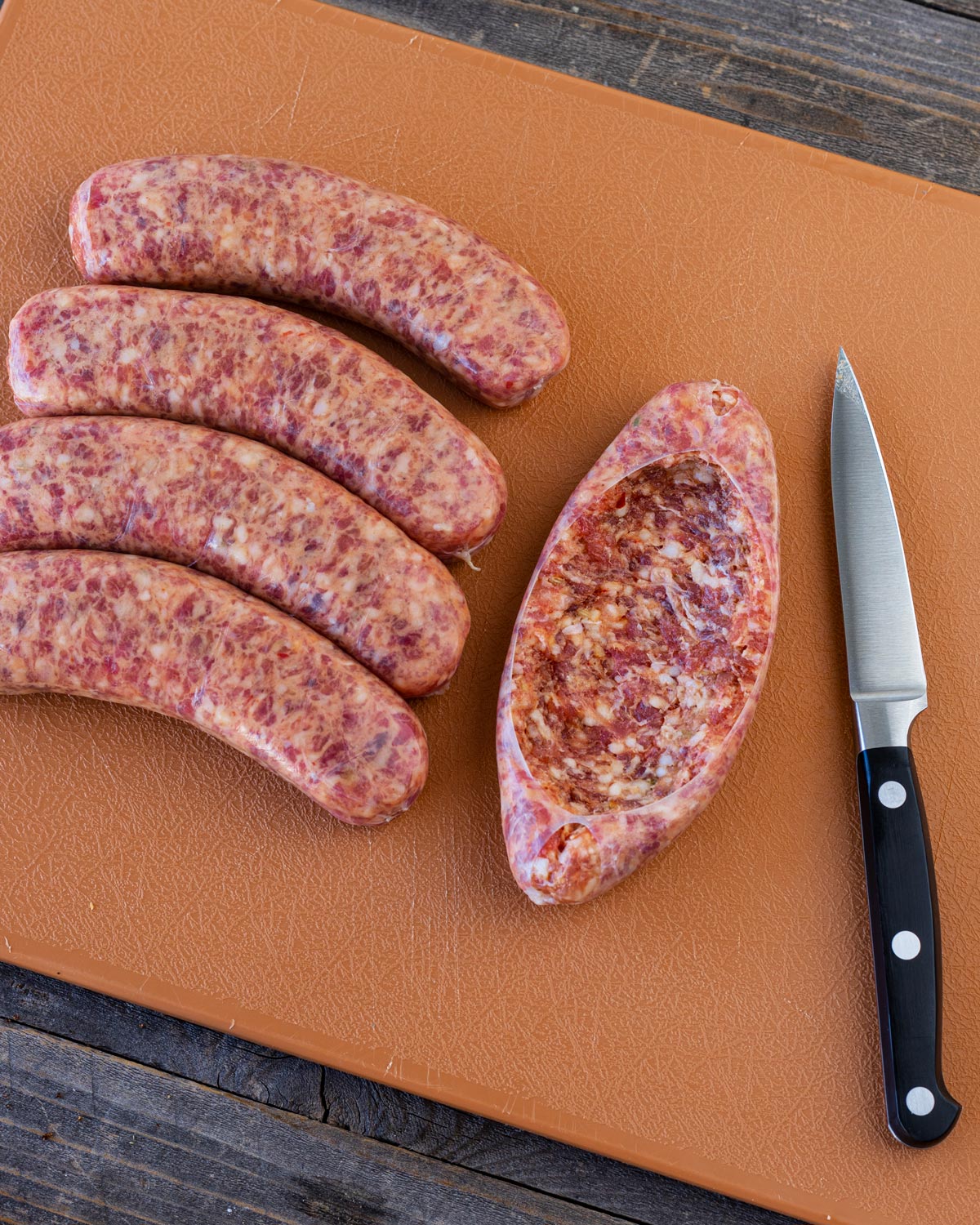 Sliced fresh sausage on a cutting board with a knife.