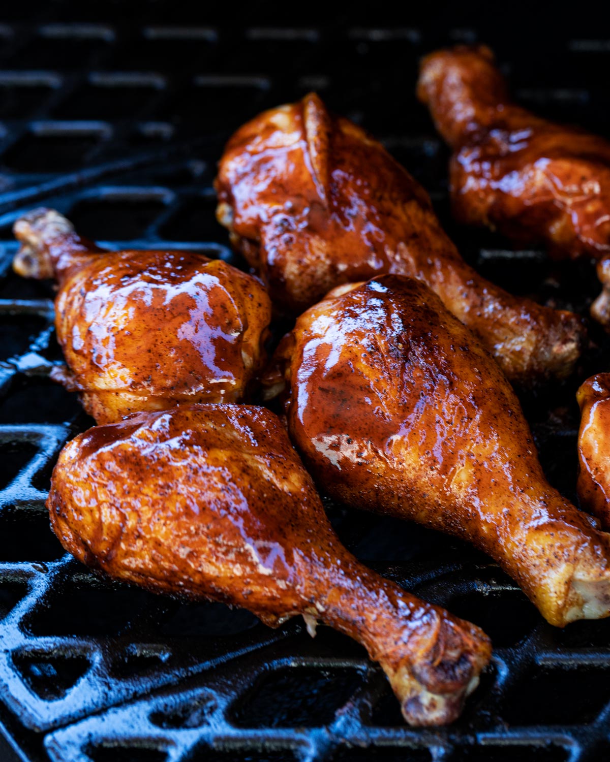 Sauced chicken legs are on the smoker grill grates.