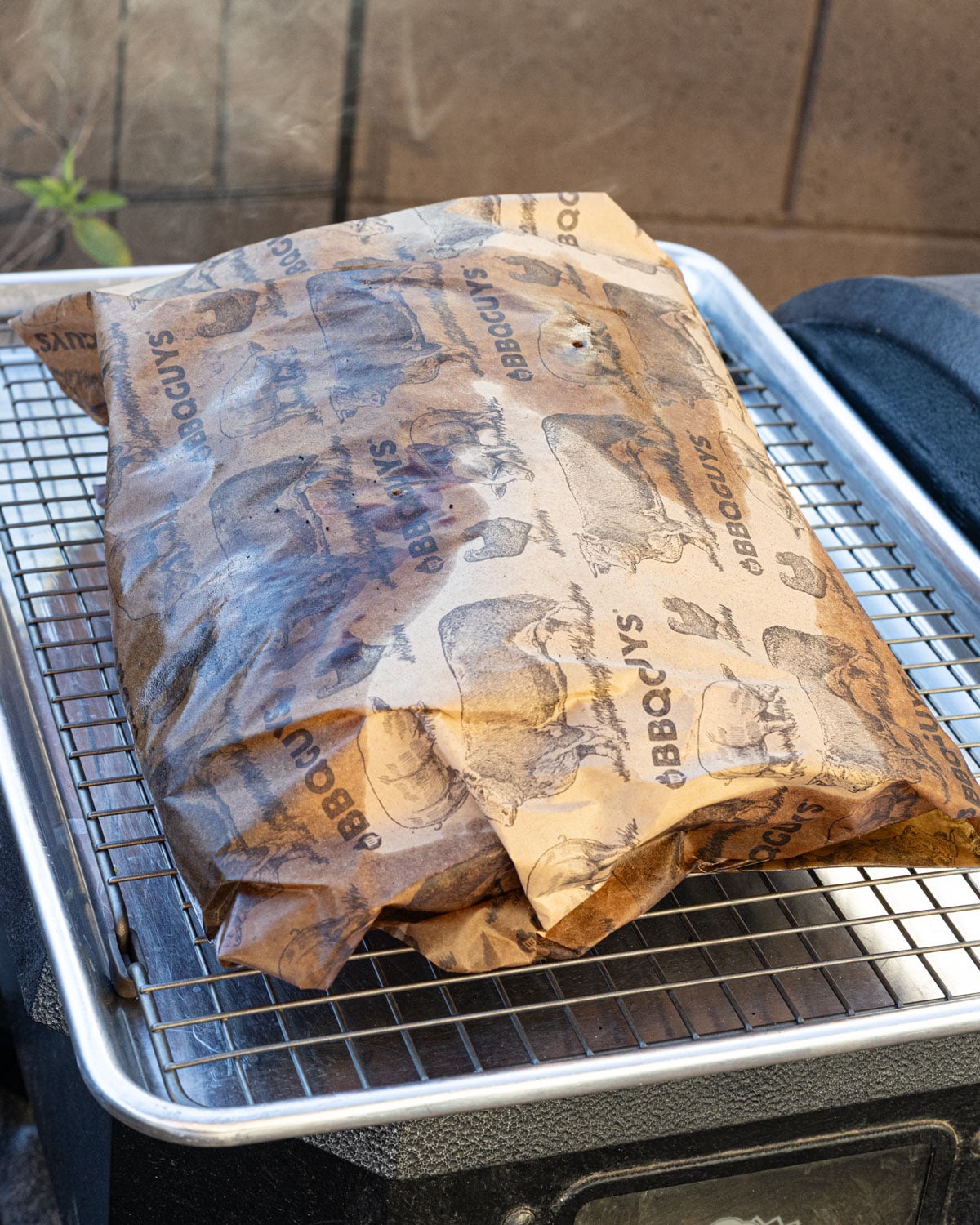 Smoked beef plate ribs wrapped in butcher paper on a wire rack resting after the cook