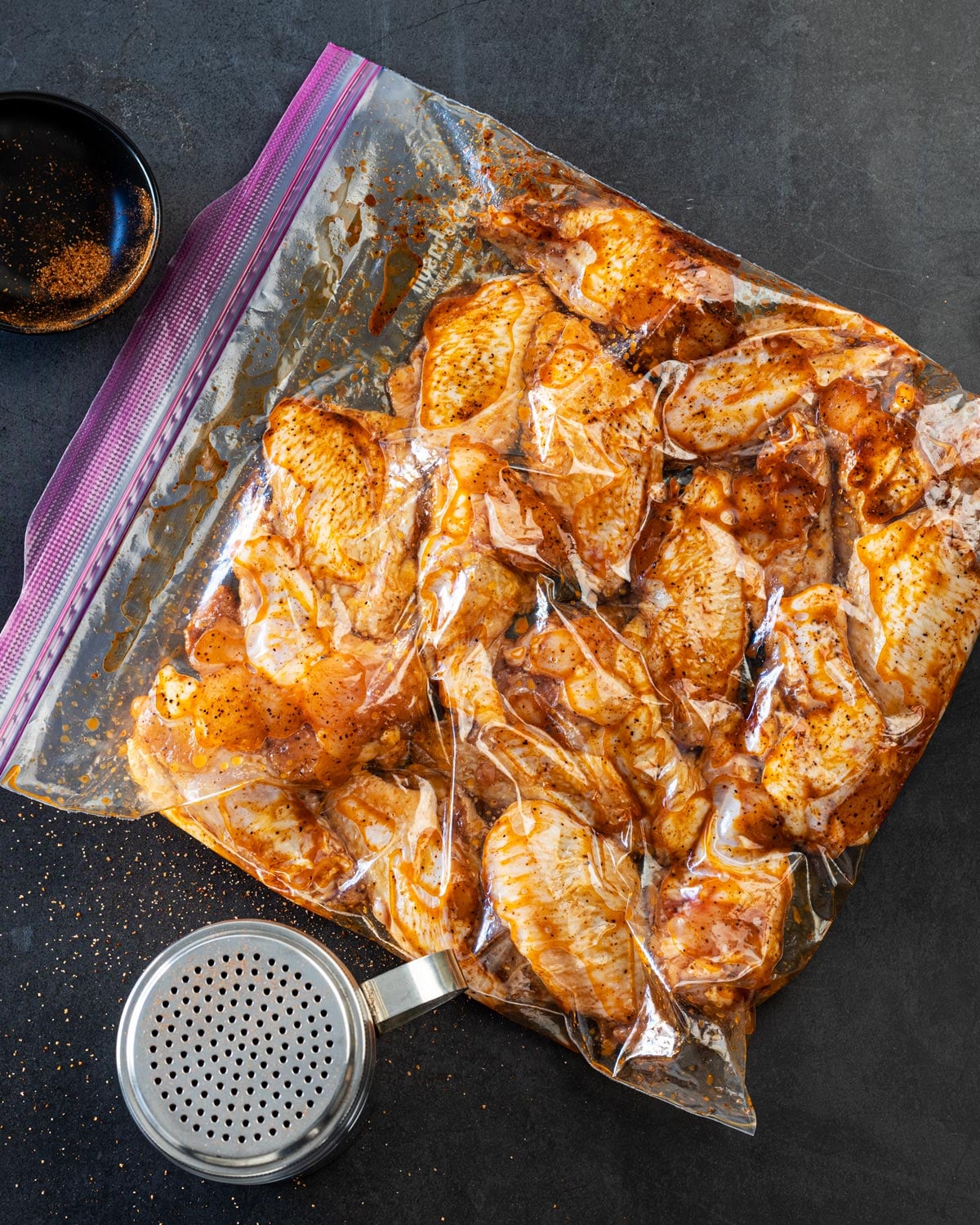 Seasoned raw chicken wings coated in oil and rub inside a resealable bag
