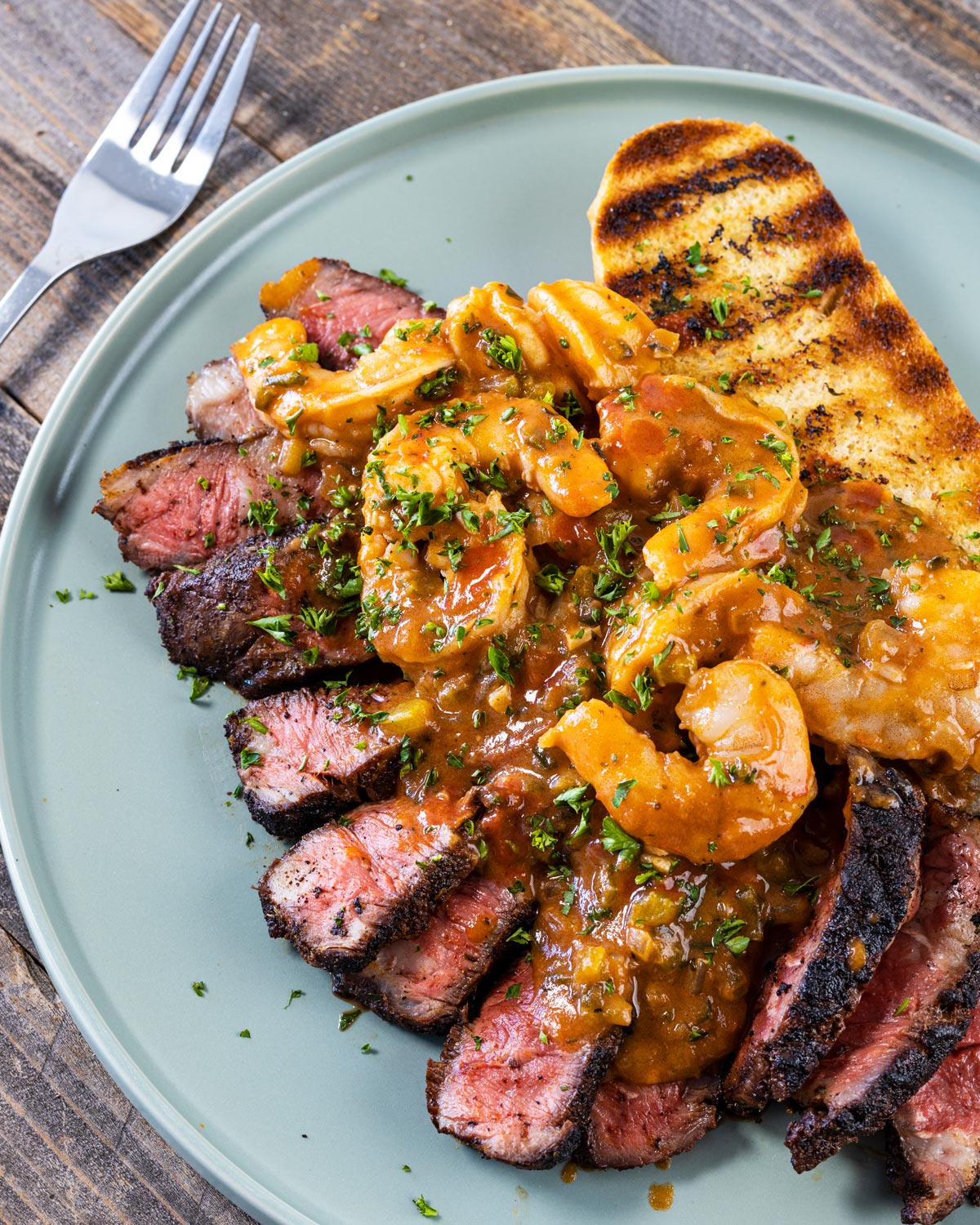 Cajun steak and shrimp etouffee are served with a crispy garlic bread.