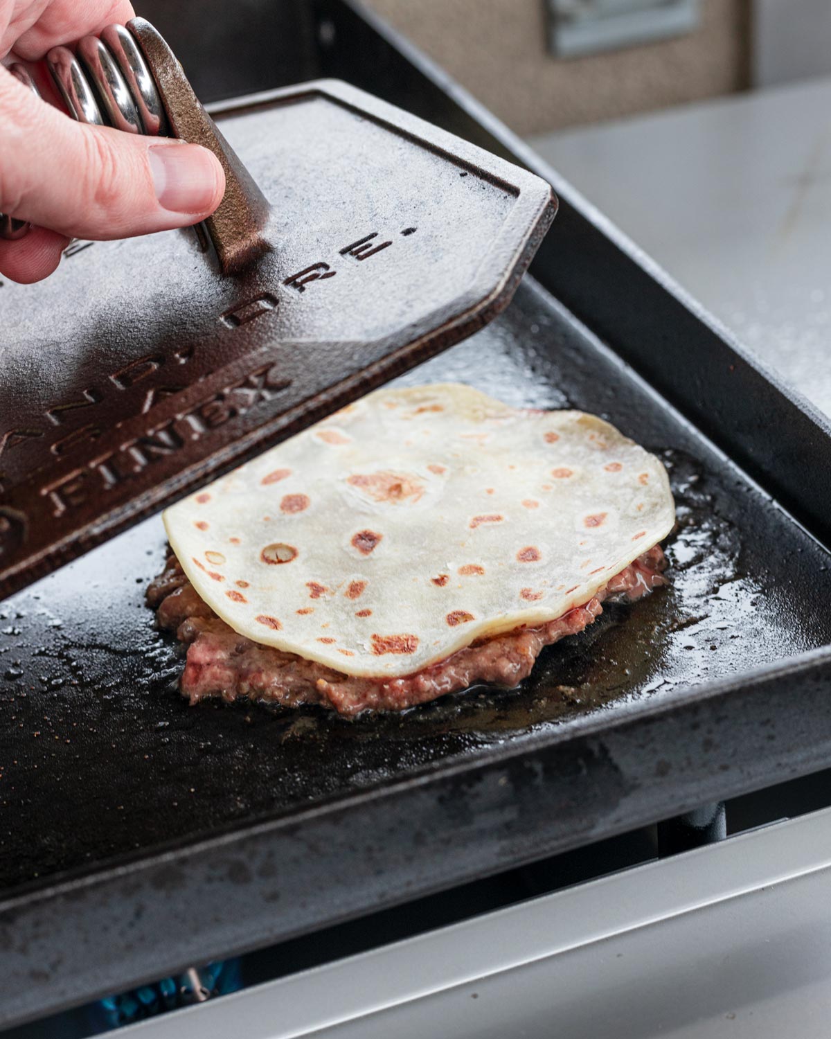 Smash the tortilla down which will press the burger into it.