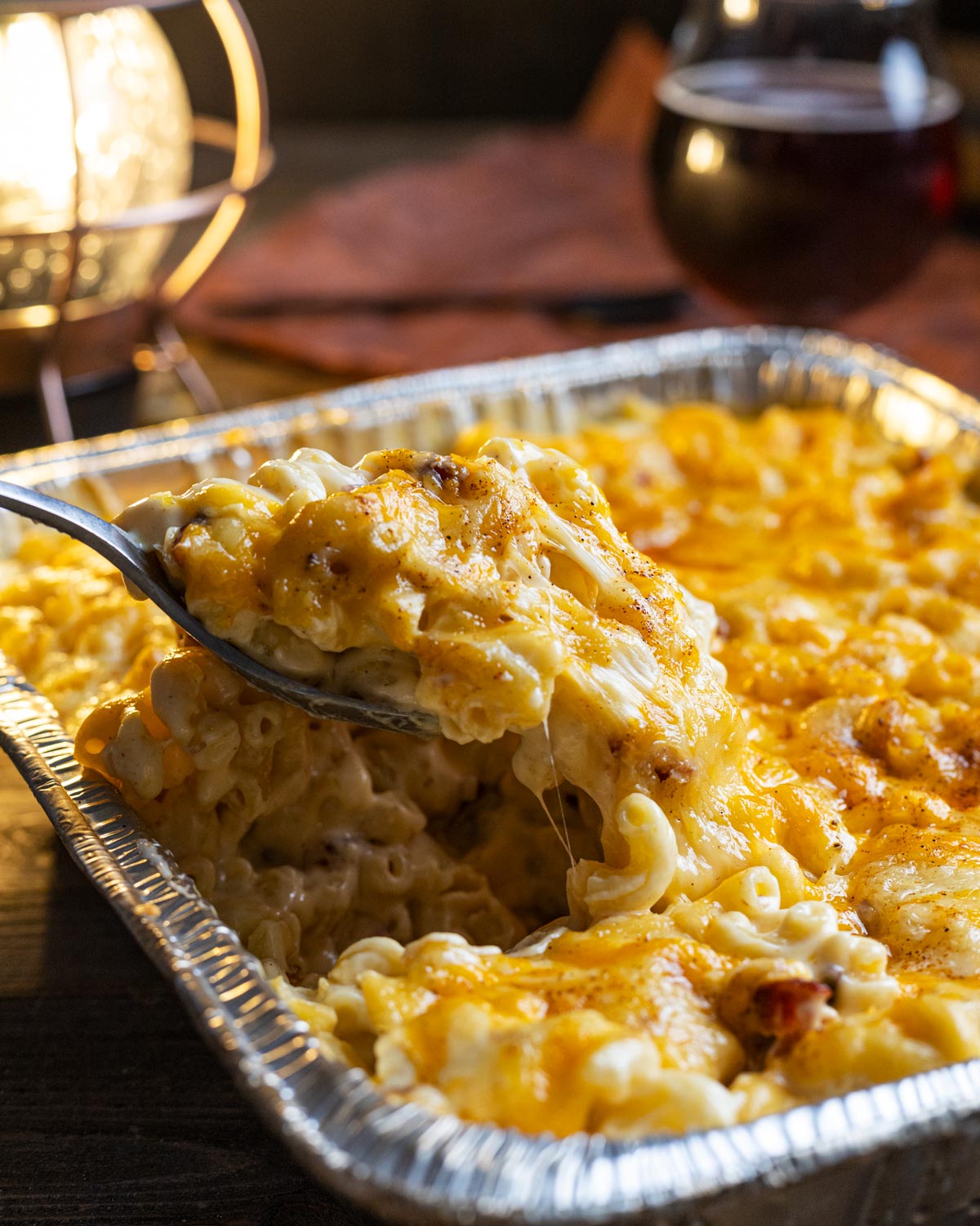 Spoonful of creamy mac and cheese pulled out of the foil tray.