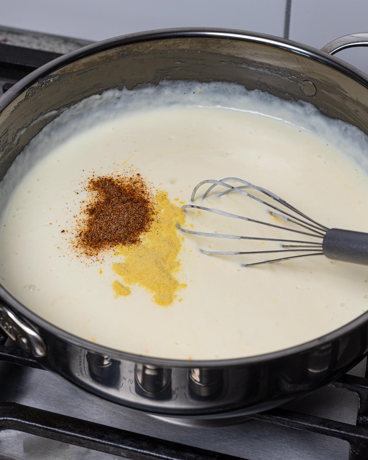 Slowly add in the warmed milk, cream, and spices to thicken the sauce.