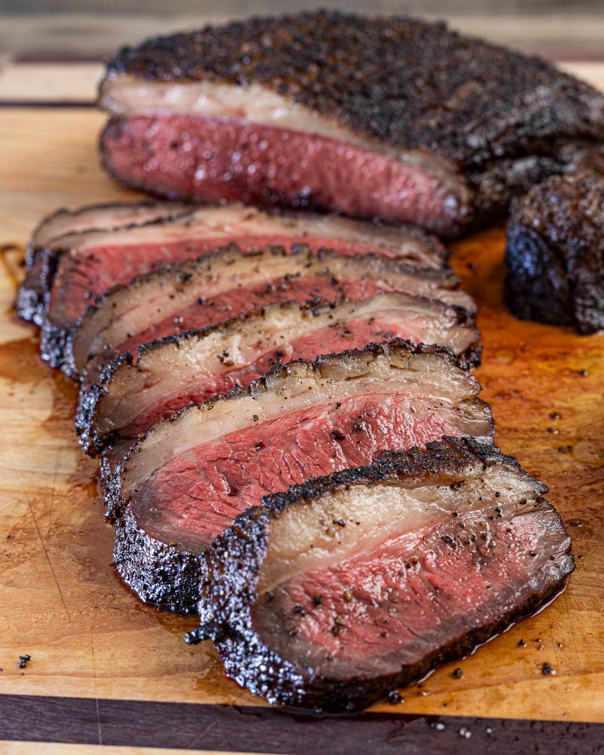 Reverse-seared picanha sliced thin on a cutting board showing pink interior and dark bark