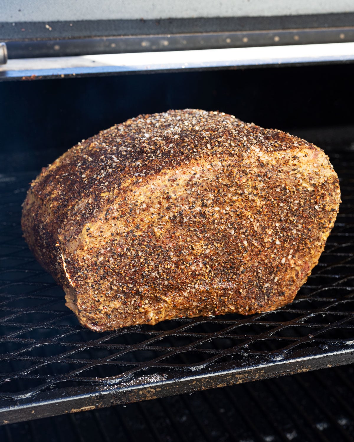 seasoned prime rib roast on the smoker grates before cooking