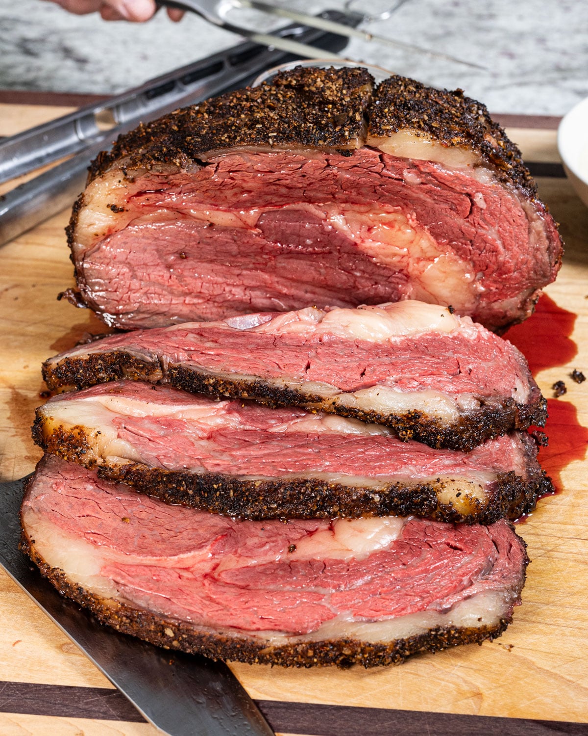 smoked prime rib sliced open to show the pink interior, on a cutting board