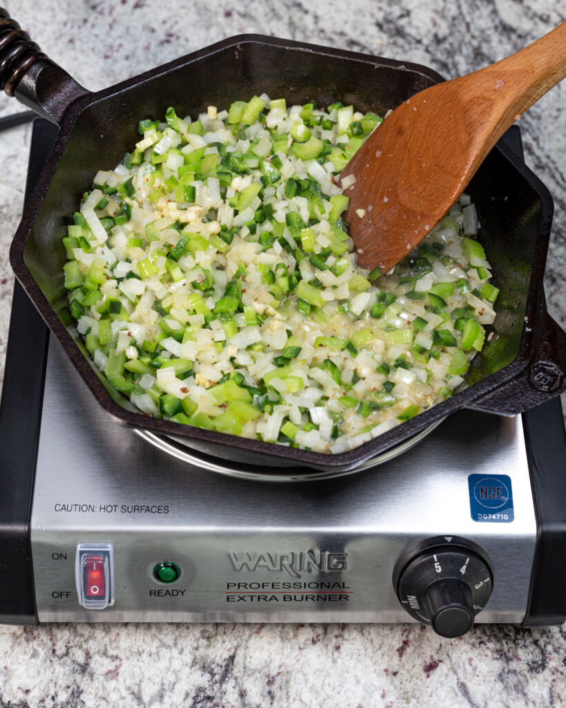 Saute the aromatics for the sausage stuffing recipe.