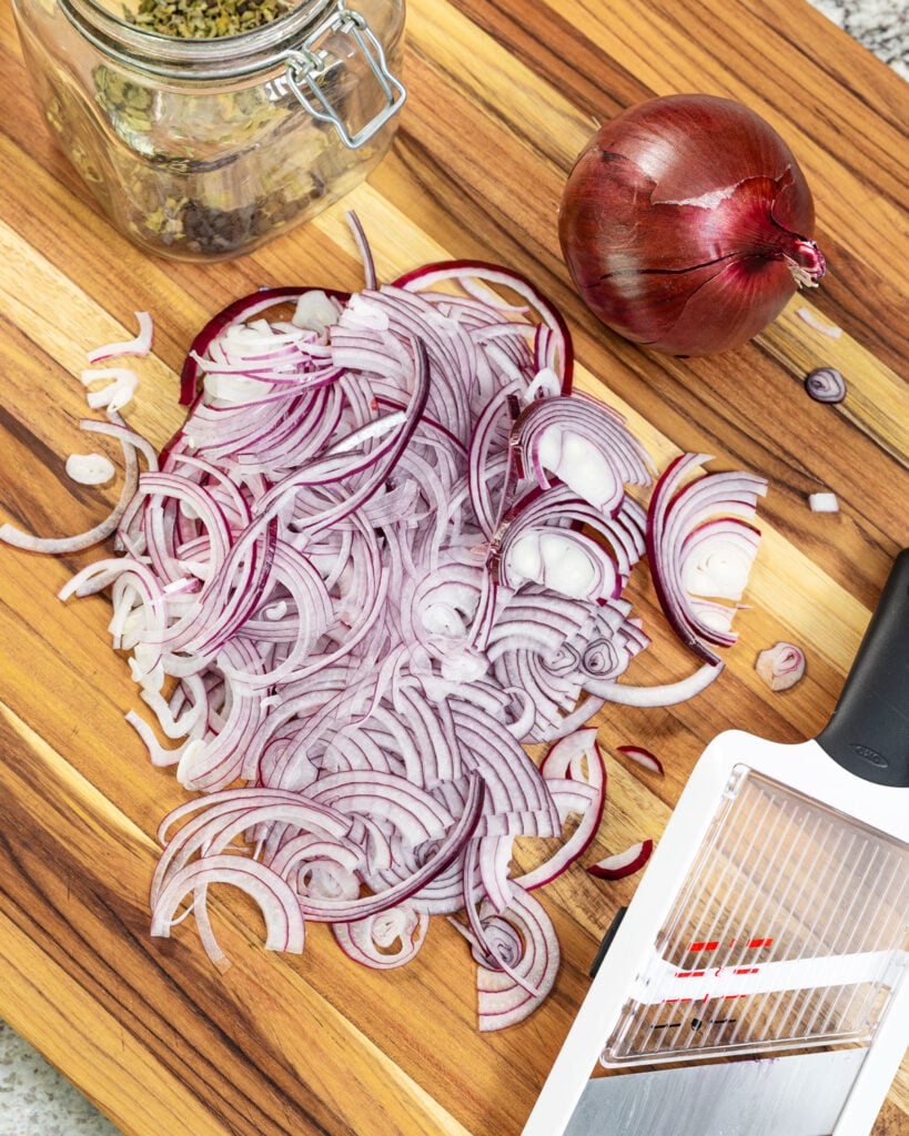 Cut the red onion in half, and then use a mandoline to slice it thin.