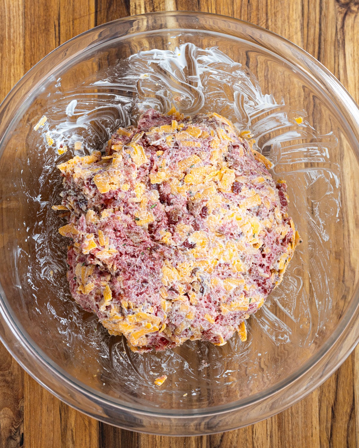 Ground beef mixed with shredded cheddar, crumbled bacon, sour cream, and ranch seasoning in a glass bowl