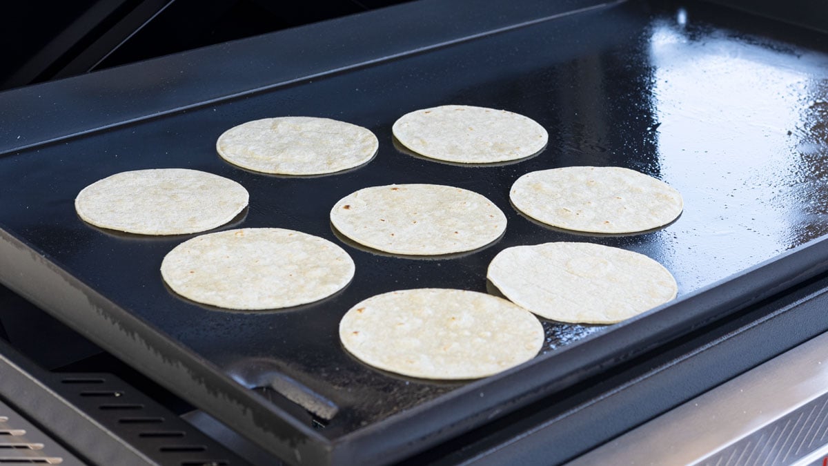 Corn tortillas warming on a hot griddle