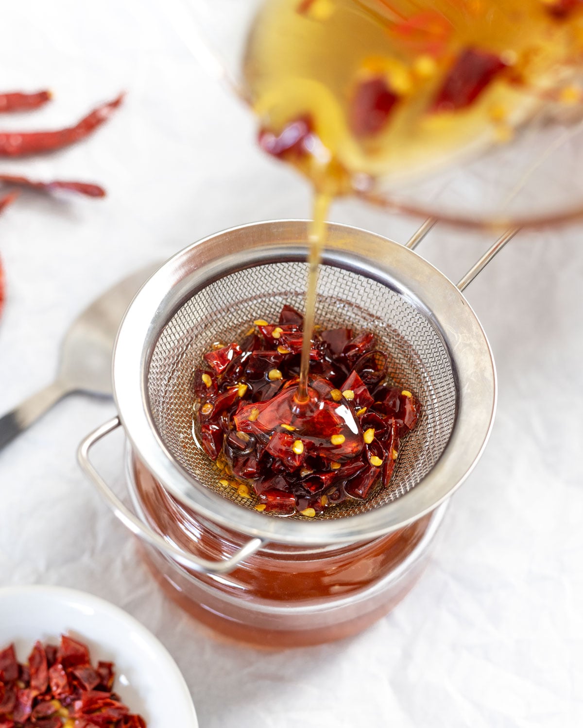 Strain out the chiles de arbol from the infused honey, which helps to keep the flavor consistent and smooth.