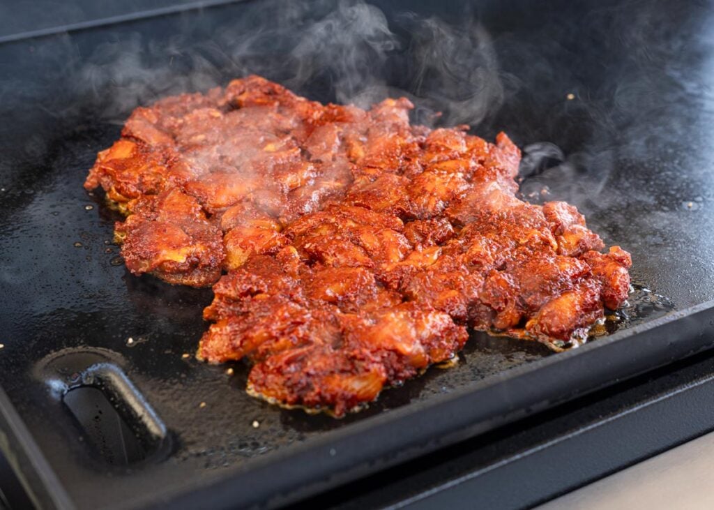 Add the marinated chicken to the hot griddle and let it sear for a few minutes.