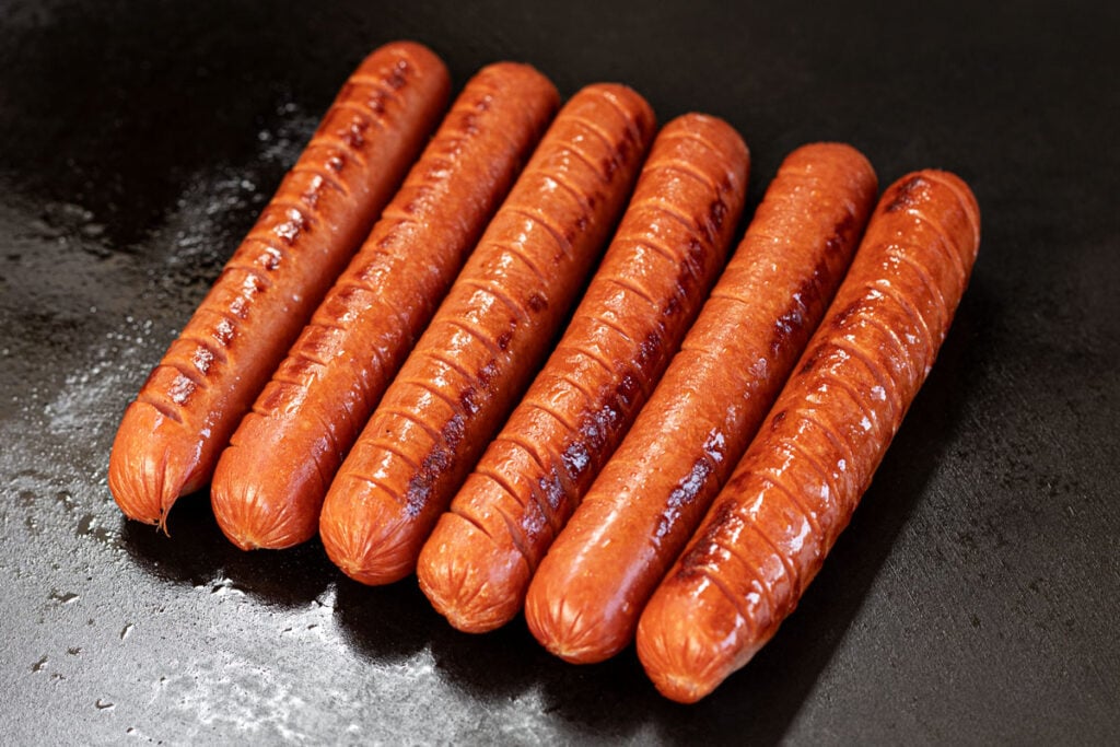 Score and sear the hot dogs for a few minutes on all sides.