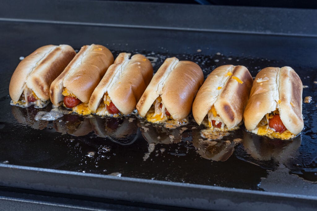 Sear the hot dogs with the cheese side facing down, creating a crispy cheese crust.