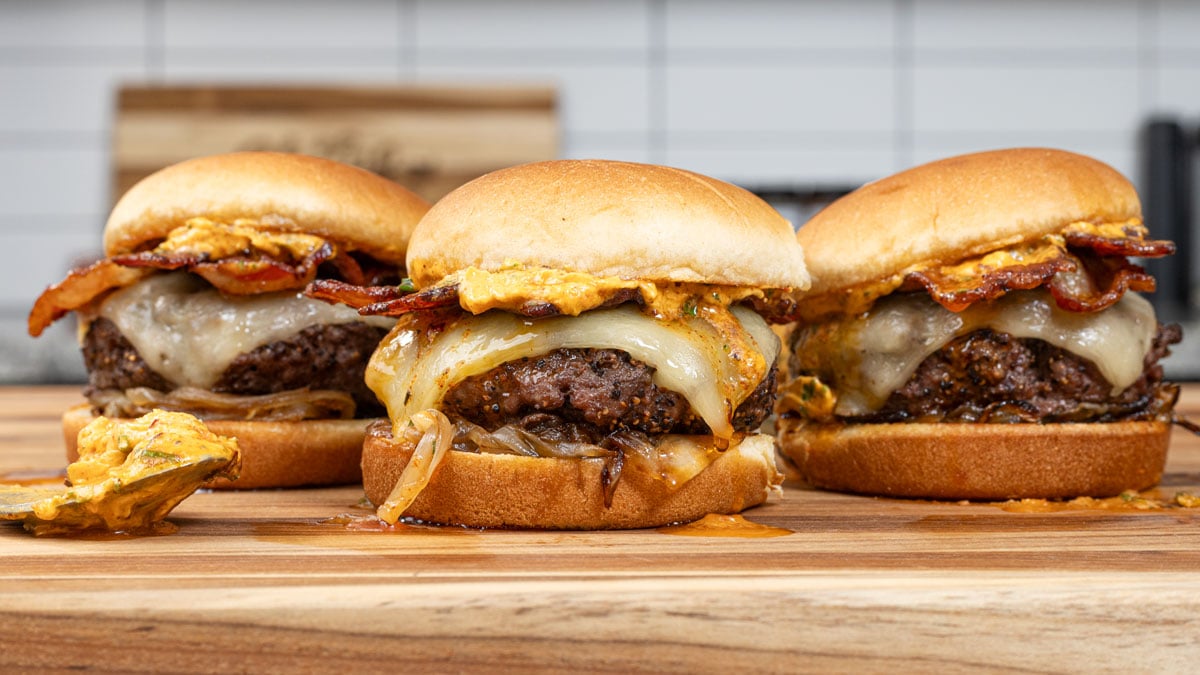 Here is a lineup of delicious butter burgers, topped with bacon, onions, and cowboy butter.