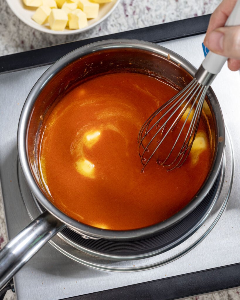 Whisking the butter into the warm hot sauce.