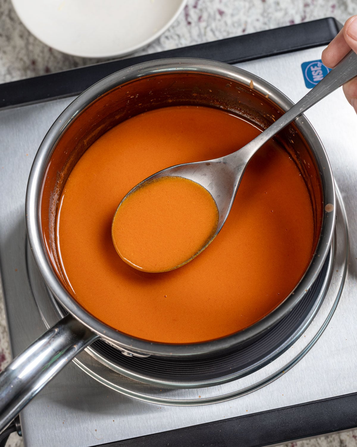 Finished creamy buffalo sauce coating the back of a spoon