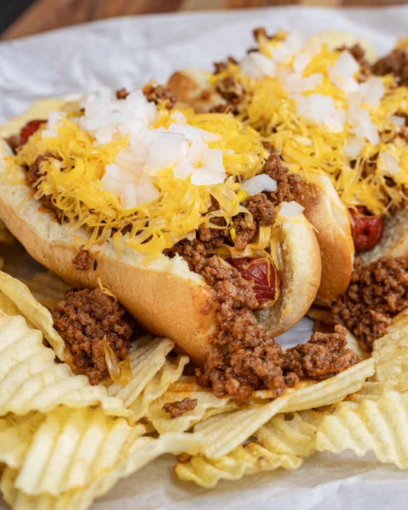 Adding cheese and onions to the best chili dogs