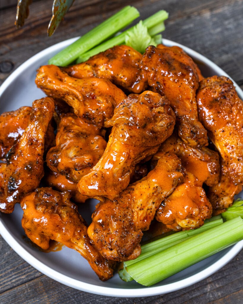 Buffalo wings glazed in hot sauce stacked on a plate