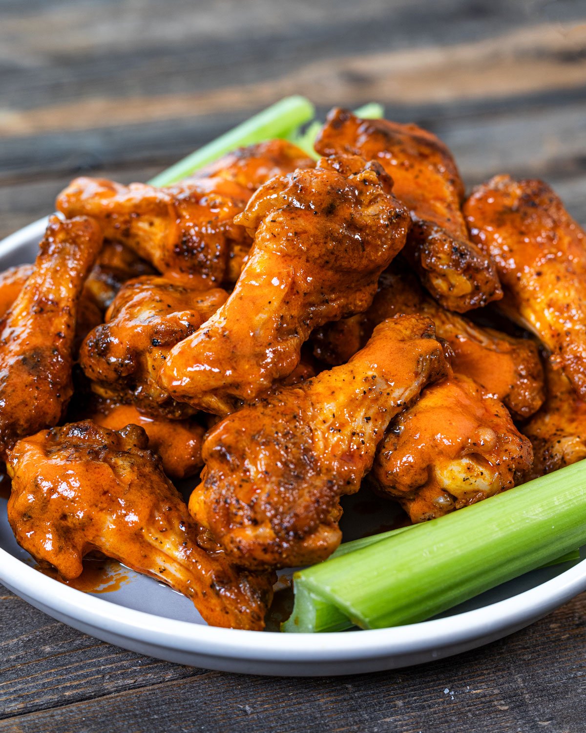 Overhead shot of grilled buffalo wings in a bowl with celery on the side.