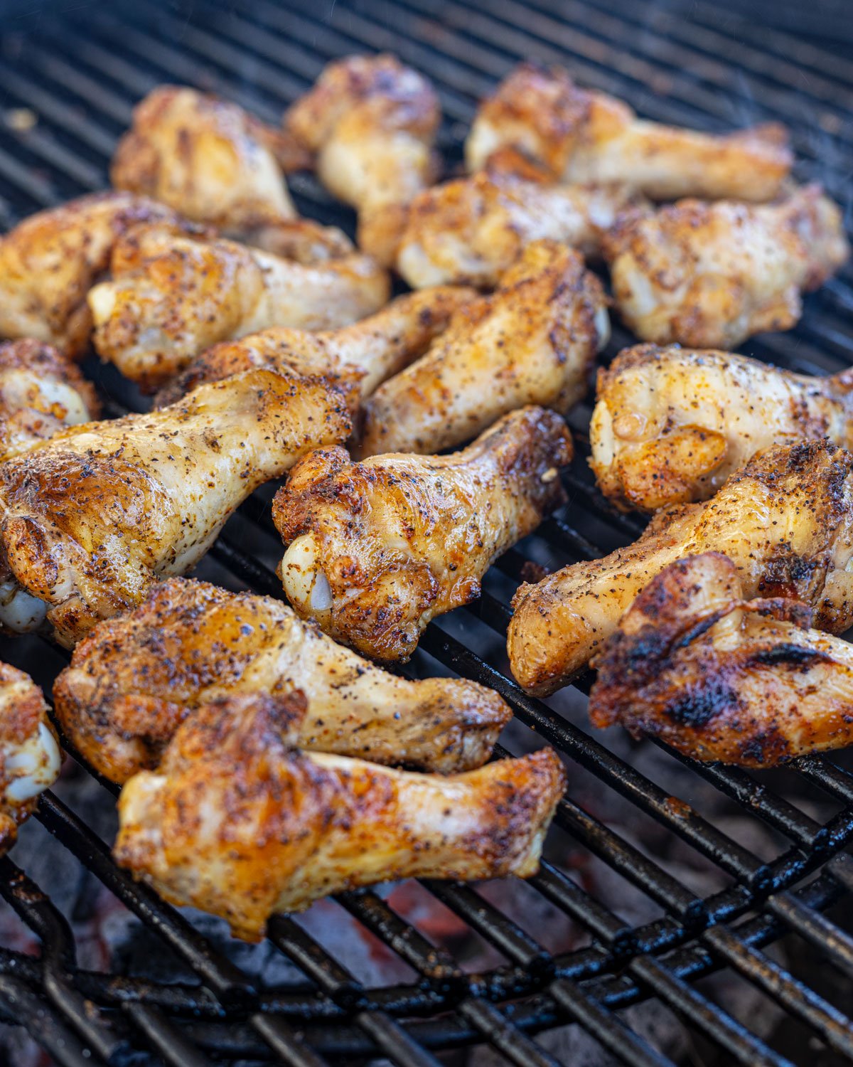 Chicken wings searing over the hot coals on a charcoal grill.