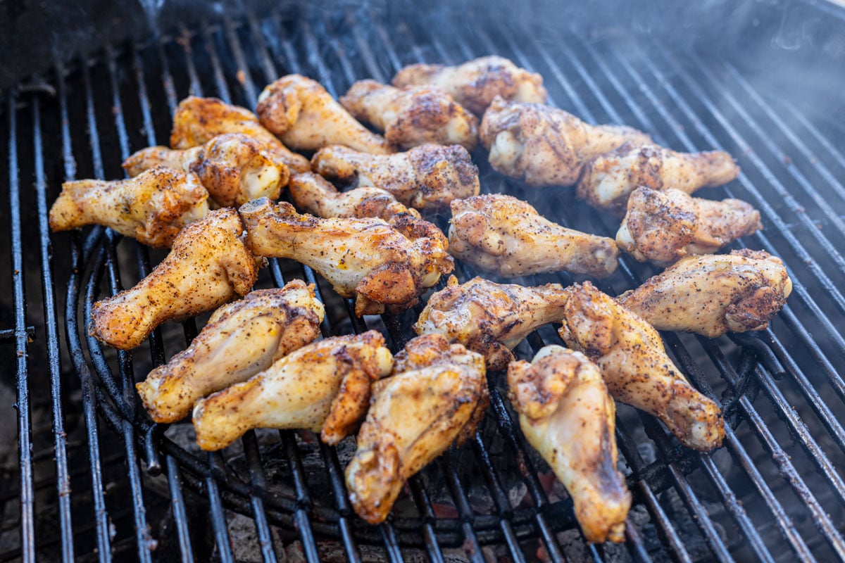 Chicken wings searing over charcoal on the grill.