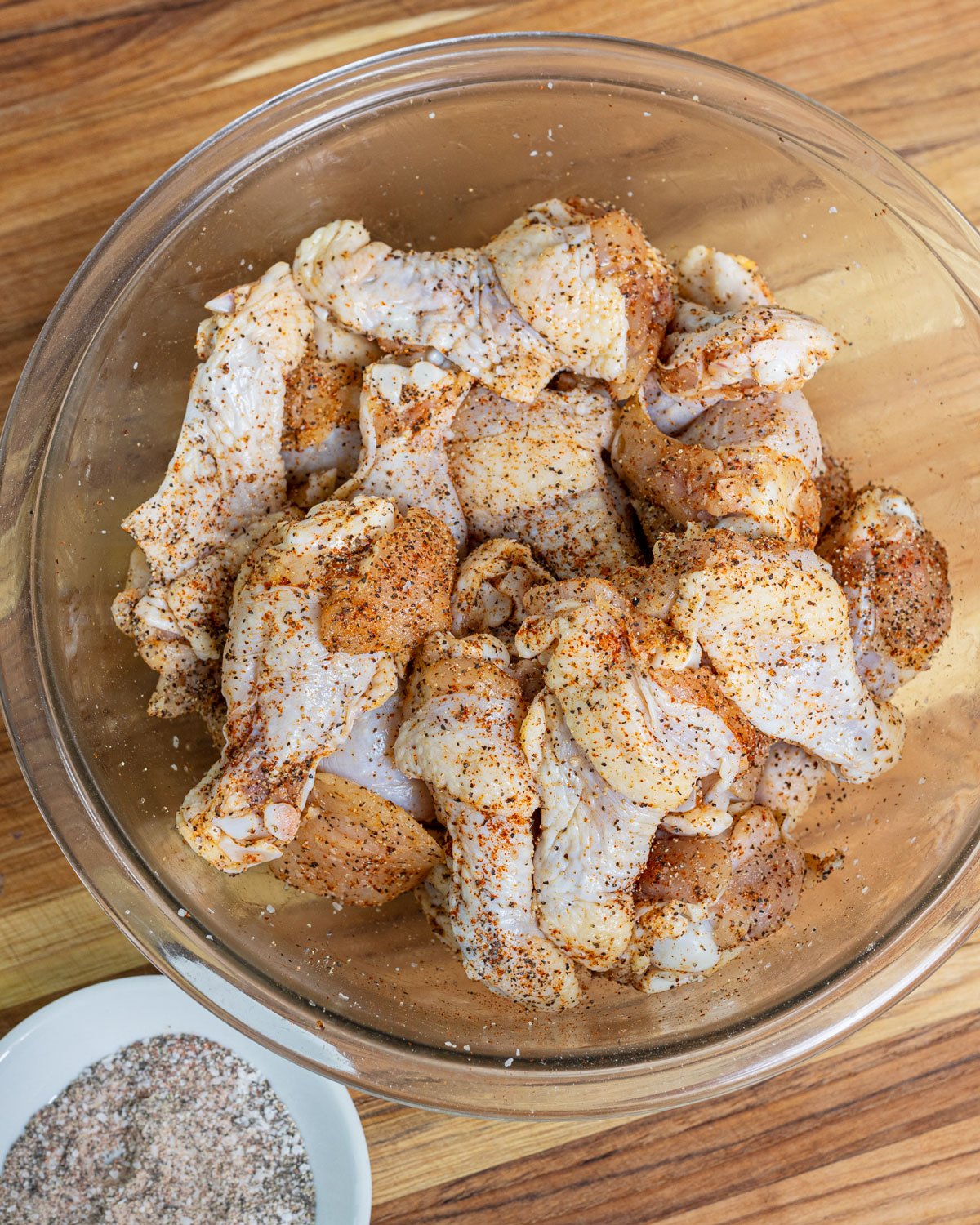 Raw wings seasoned in a mixing bowl.