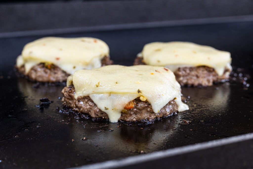 Place melty cheese on top of the chiles and burgers.