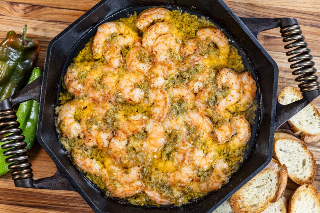 This is a skillet with spicy shrimp in melted chile butter and crispy bread.