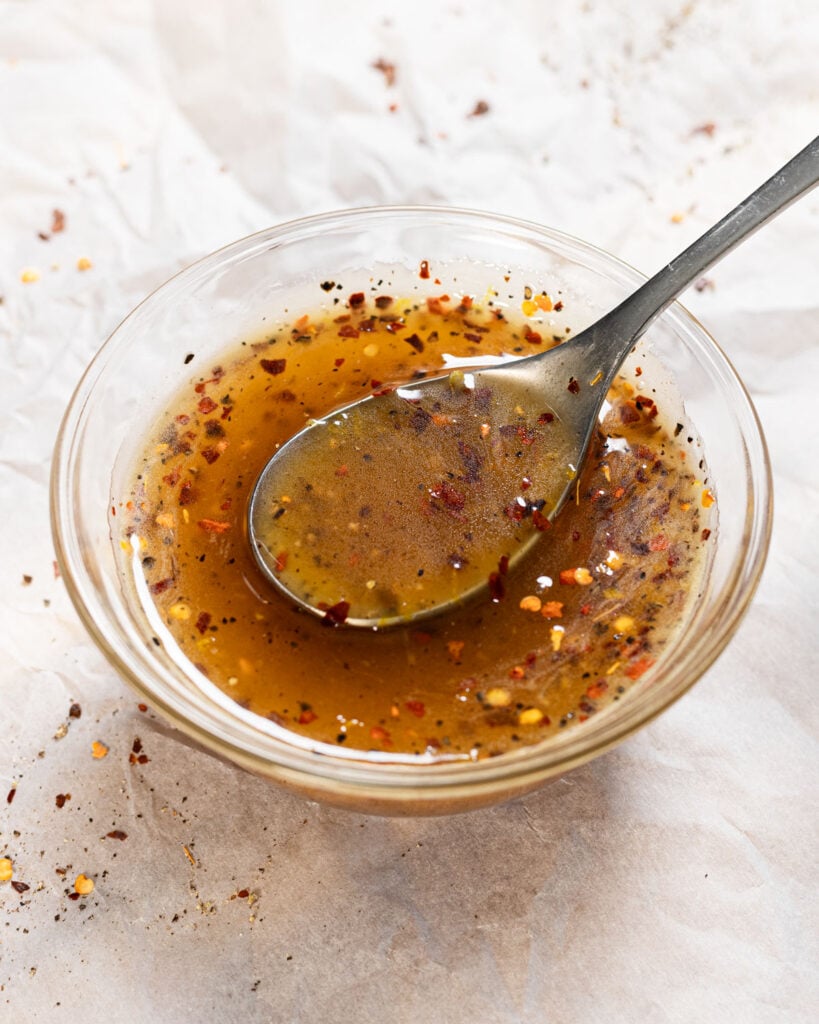 Hot honey lemon pepper sauce in a small bowl with a spoon.