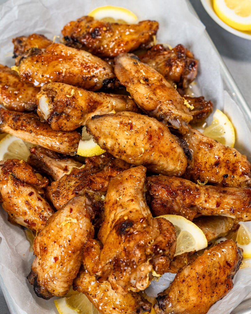 Hot honey lemon pepper wings served in a sheet pan with extra lemon slices.