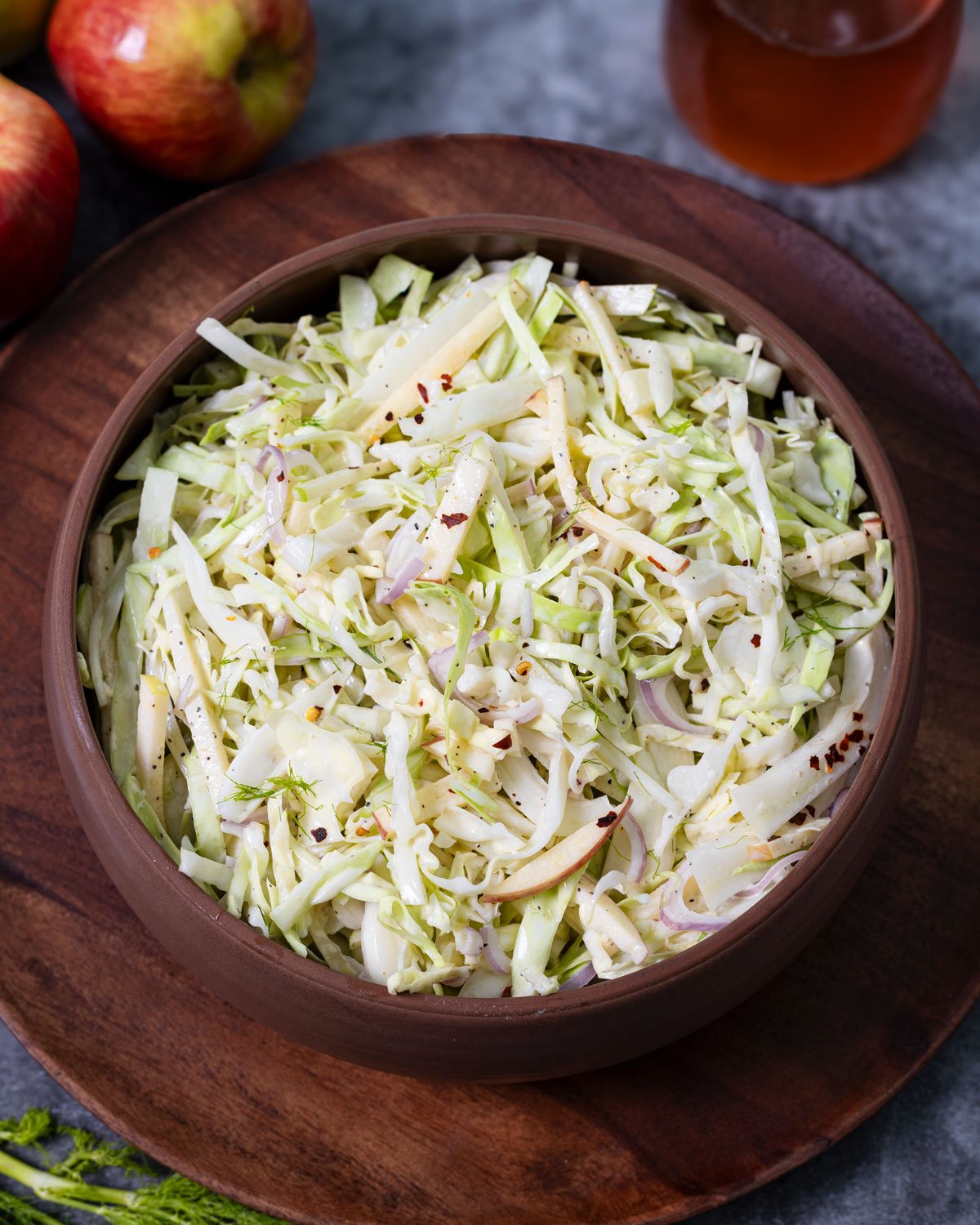 Apple fennel slaw served in a serving bowl with chile flakes on top.