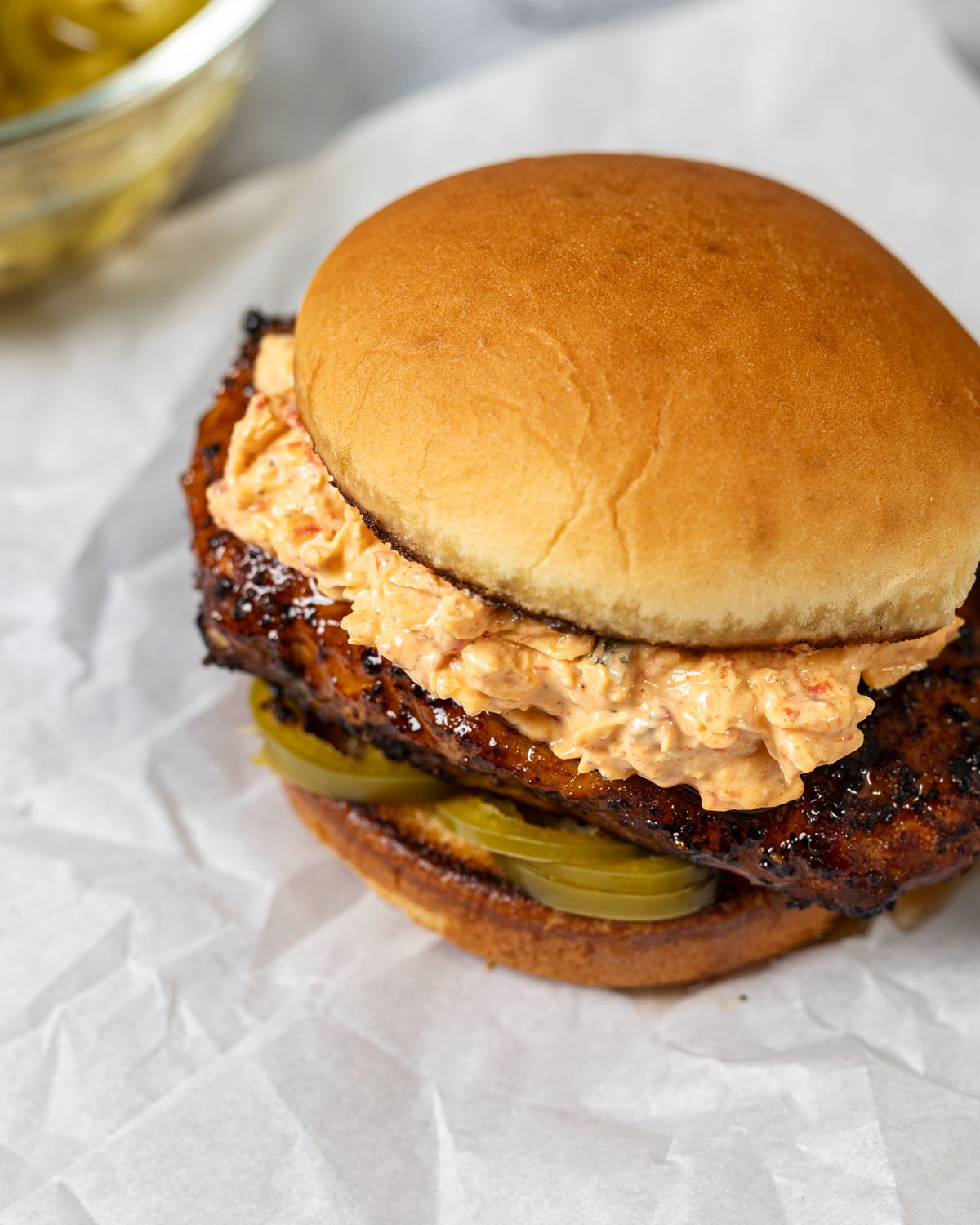 Honey pepper pimento chicken sandwich assembled and on white parchment paper.