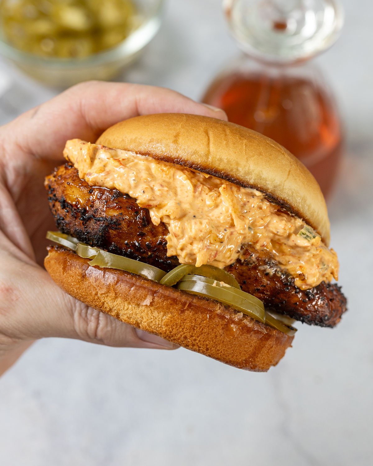 Hand holding a honey pepper pimento chicken sandwich.