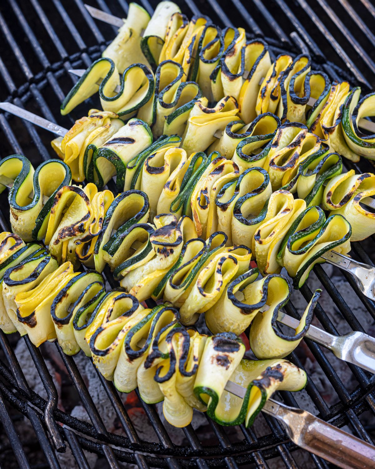 Zucchini and squash skewers on the grill after being flipped.