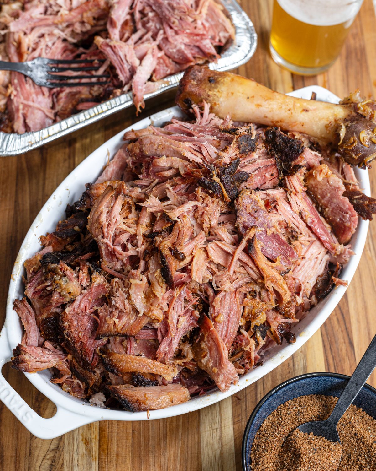 Smoked pulled ham in a dish on a cutting board with seasoning
