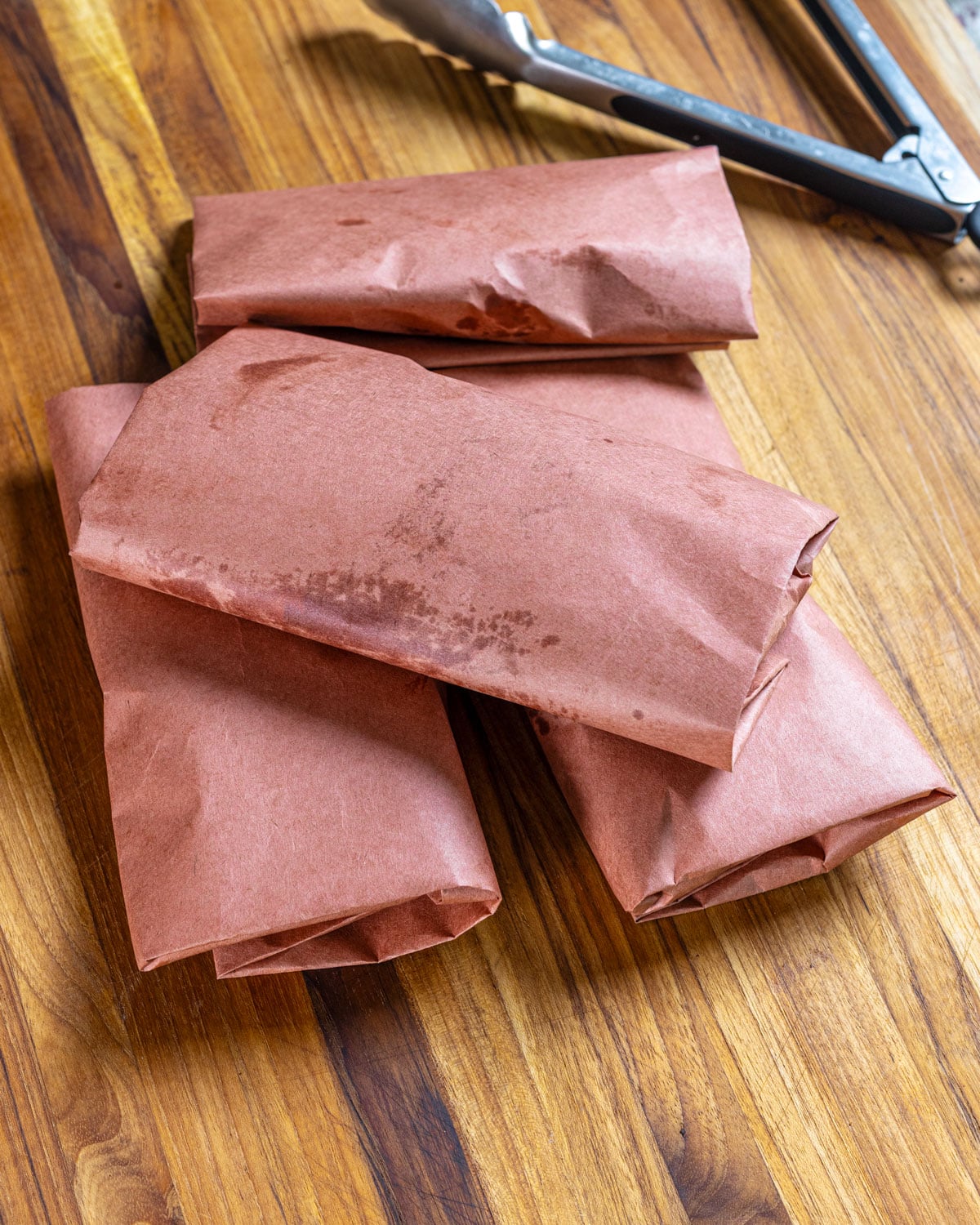 Four chicken breasts wrapped in pink butcher paper.